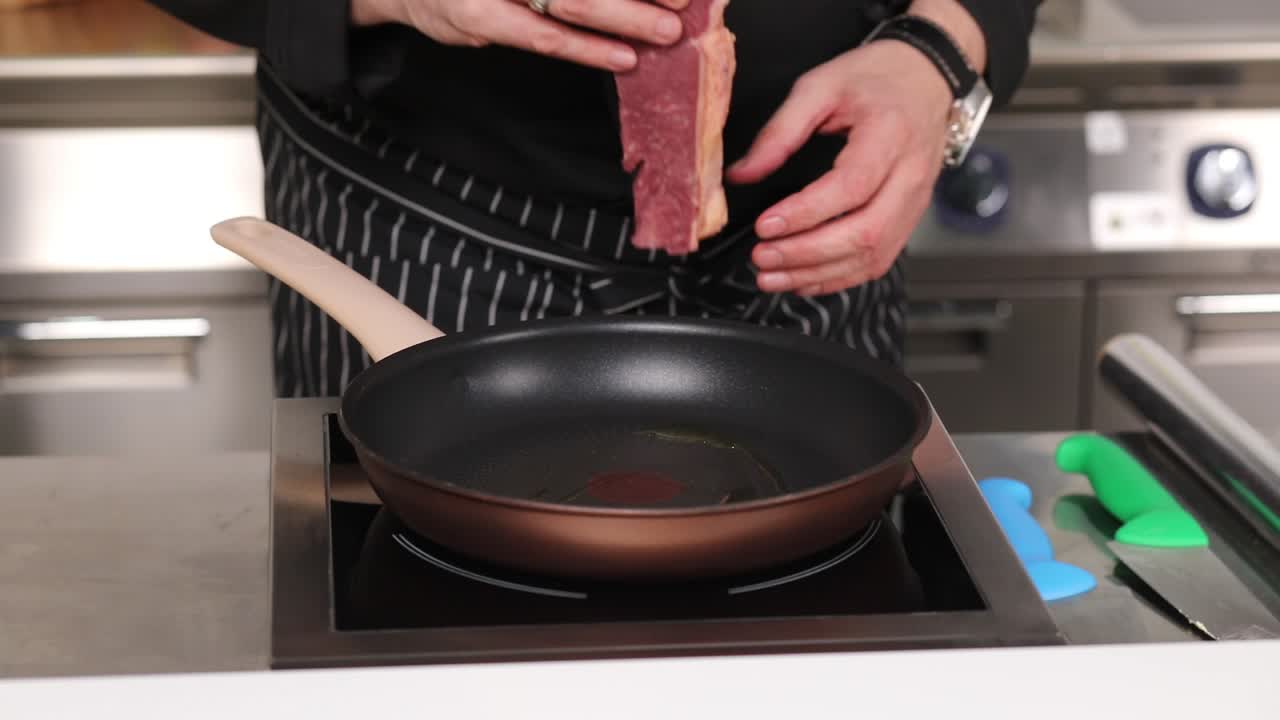 요리사 가 팬 에 스테이크 를 조리 하고 있다