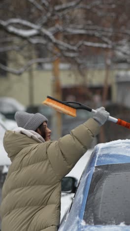 woman clearing snow from a car in winter