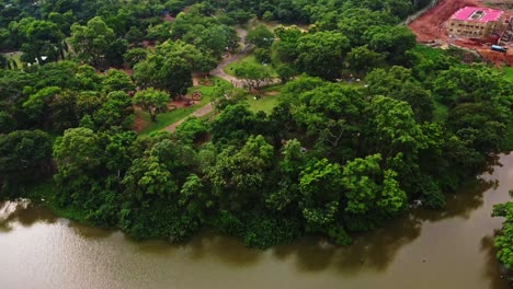 Beautiful-aerial-overview-of-lush-and-green-park-at-the-edge-of-a-large-lake-in-Abuja,-the-capital-of-Nigeria,-Africa