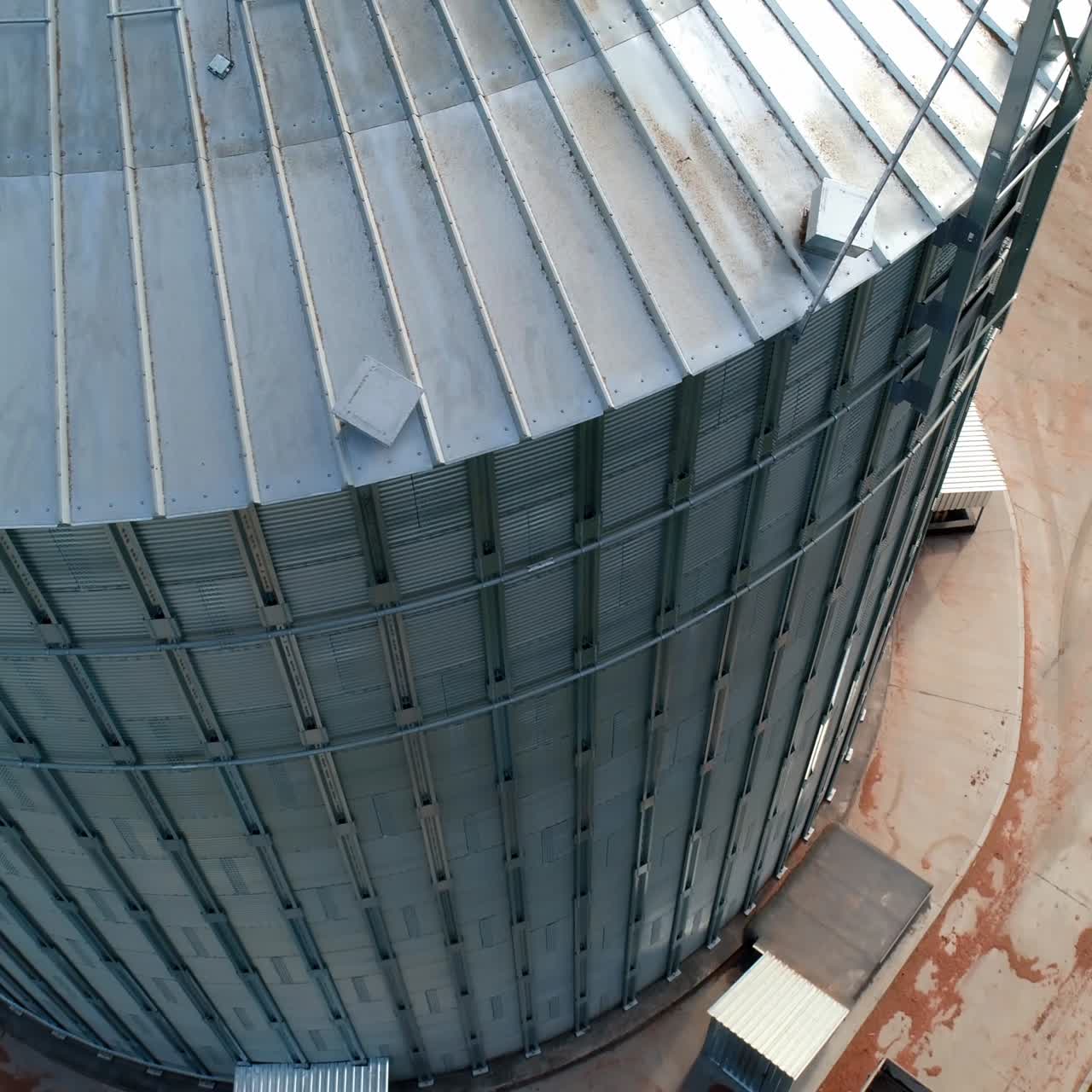 Large grain elevator. Industrial equipment for agricultural crop. Modern silver hangar. Metal bin for storing grains. Close-up.