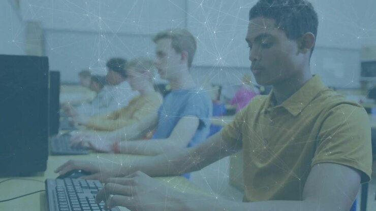 Starting with close keyboard typing, panning to teens working on keyboards and mice in computer lab
