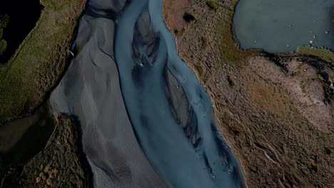 breathtaking max view tracking shot of a river, that flows through a stony and barren landscape, sunny day, daylight, no people, wilderness, outdoor