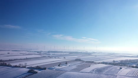 weinviertel, zistersdorf, lower austria에서 안개가 자욱한 아침 동안 회전하는 풍차가 있는 겨울 농장