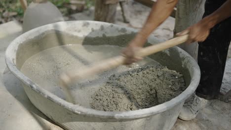 person mixing cement and gravel in a basin