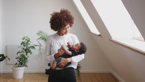 loving mother holding newborn baby son at home in loft apartment