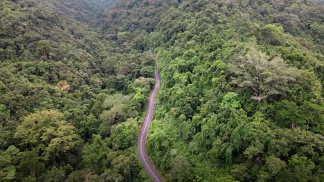Aerial-view-of-remote-road-over-top-of-mountain-with-green-jungle-in-Sumbawa-Island,-Indonesia