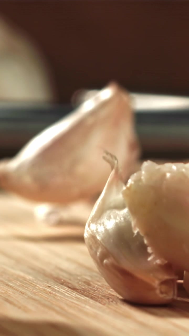 Spicchi d'aglio che cadono su un tagliere di legno al rallentatore