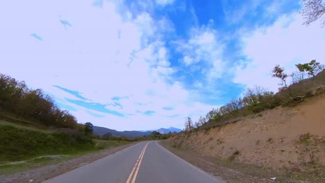 pov driving down country road. mountain in view