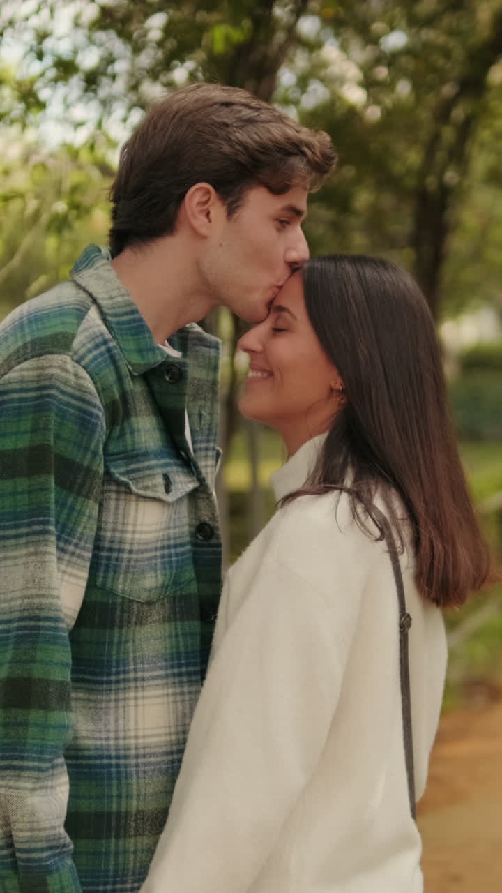 Happy young lovers man and woman standing holding hands against green arch