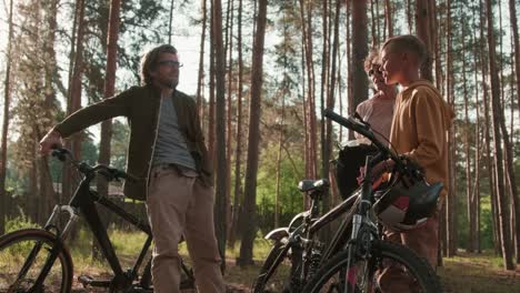 young affectionate couple with their son talking each other with their bicycles in rural environment