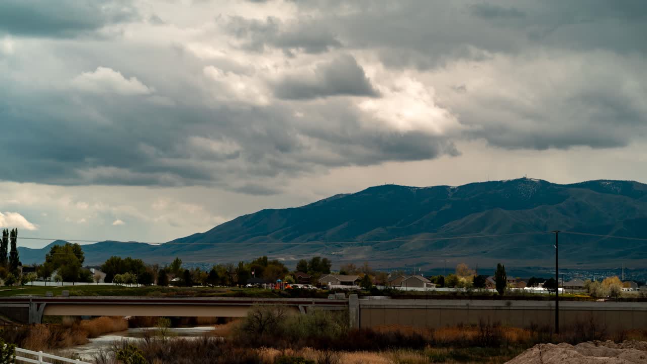 el lapso de tiempo del paisaje nublado sobre una montaña, una carretera y una comunidad suburbana - panorama