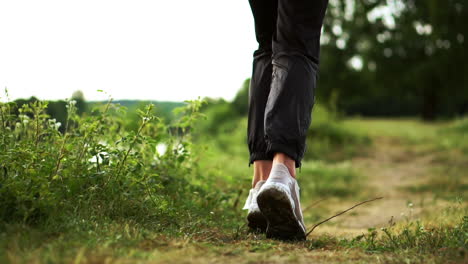 primer plano de pies corriendo en zapatillas a lo largo del río en el césped