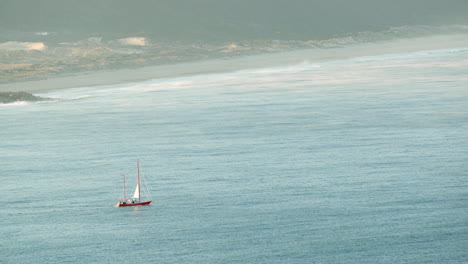 boat sailing at blue sea near north beach in nazare, portugal at sunrise