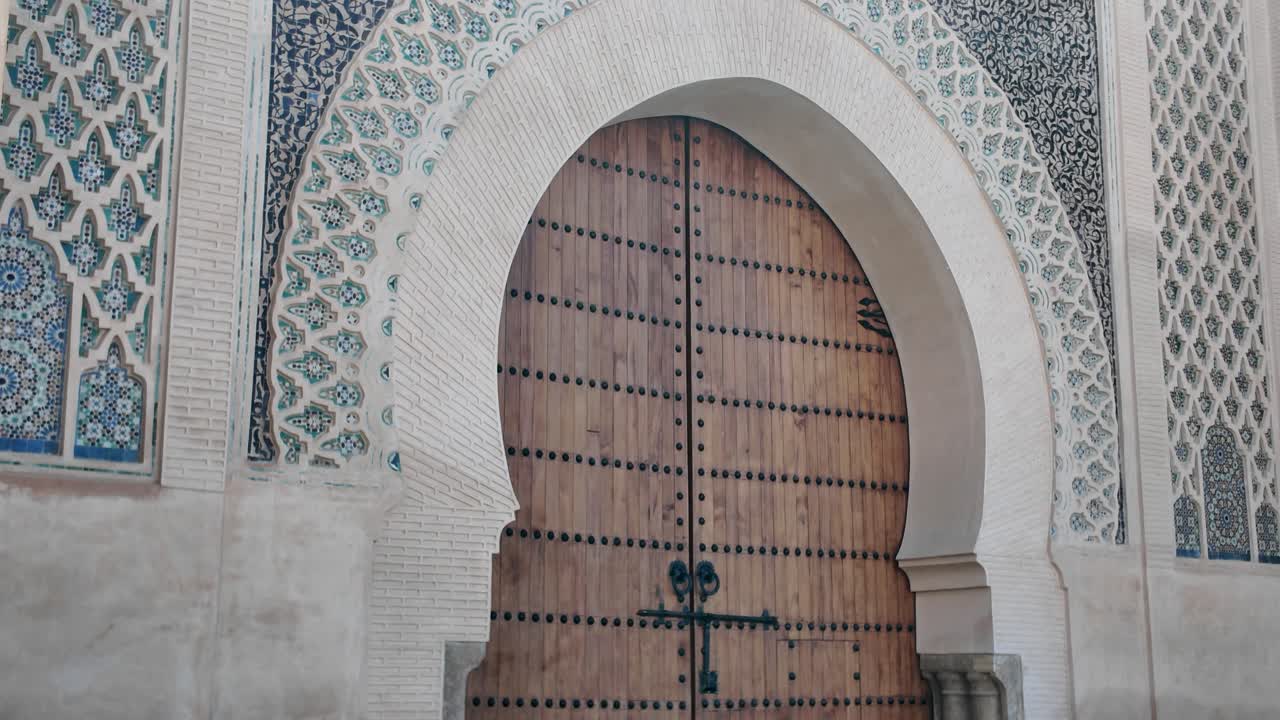 Ancient Moroccan architecture with ornate tile designs and a wooden gate in Meknes