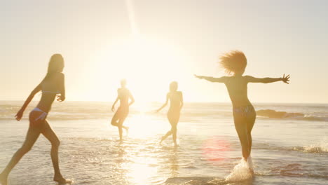 group of friends play in waves at sunset together on beach vacation