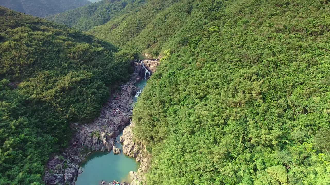 revelación aérea de una hermosa cascada escondida entre el valle de la montaña