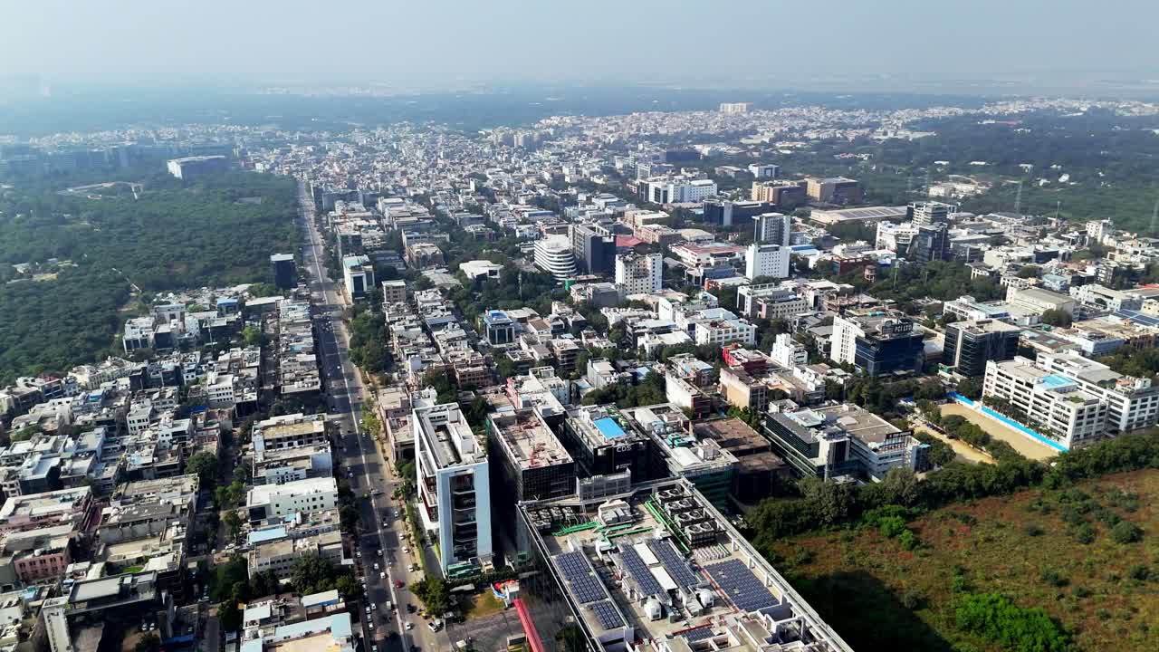 Una ripresa aerea (con drone) ampia o orbitante che cattura il moderno skyline di grattacieli di Gurugram, Haryana, India. L'inquadratura mostra in primo piano le torri per uffici in vetro della rinomata DLF Cyber City.