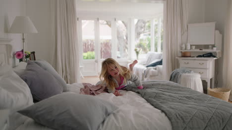 adorable little girl jumping on bed having fun child in playful mood enjoying weekend morning at home