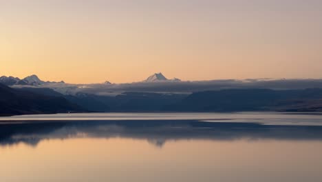 peaceful golden hour over large lake and snowy mountains