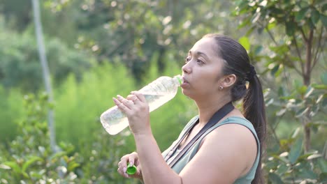 Young-Latin-woman-drinking-water-during-hiking-in-the-forest