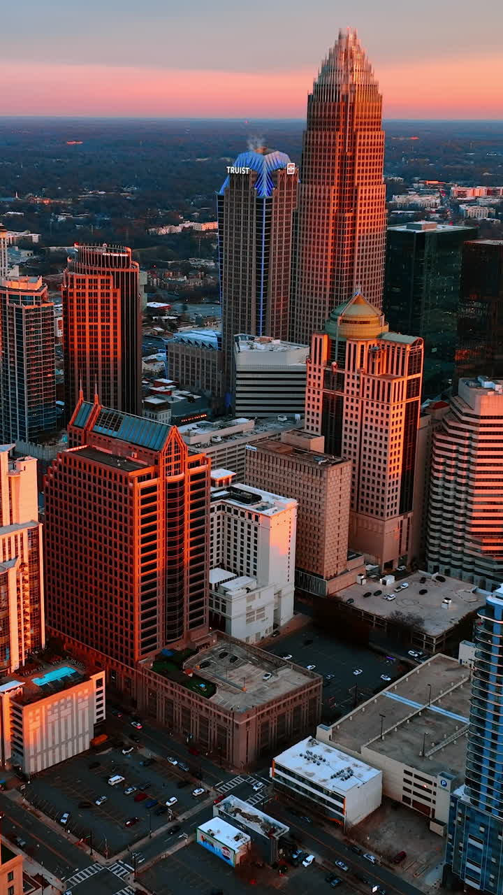 Facciate di grattacieli alla luce del sole al tramonto. Filmato aereo che si avvicina ai grattacieli del centro di Charlotte, Carolina del Nord, USA. Video verticale