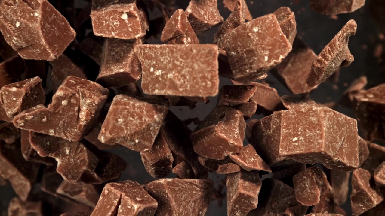 Pezzi di cioccolato che cadono al rallentatore su uno sfondo scuro