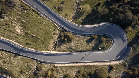 aerial top view of a skater practicing downhill down a road in the middle of the forest in andorra - europe