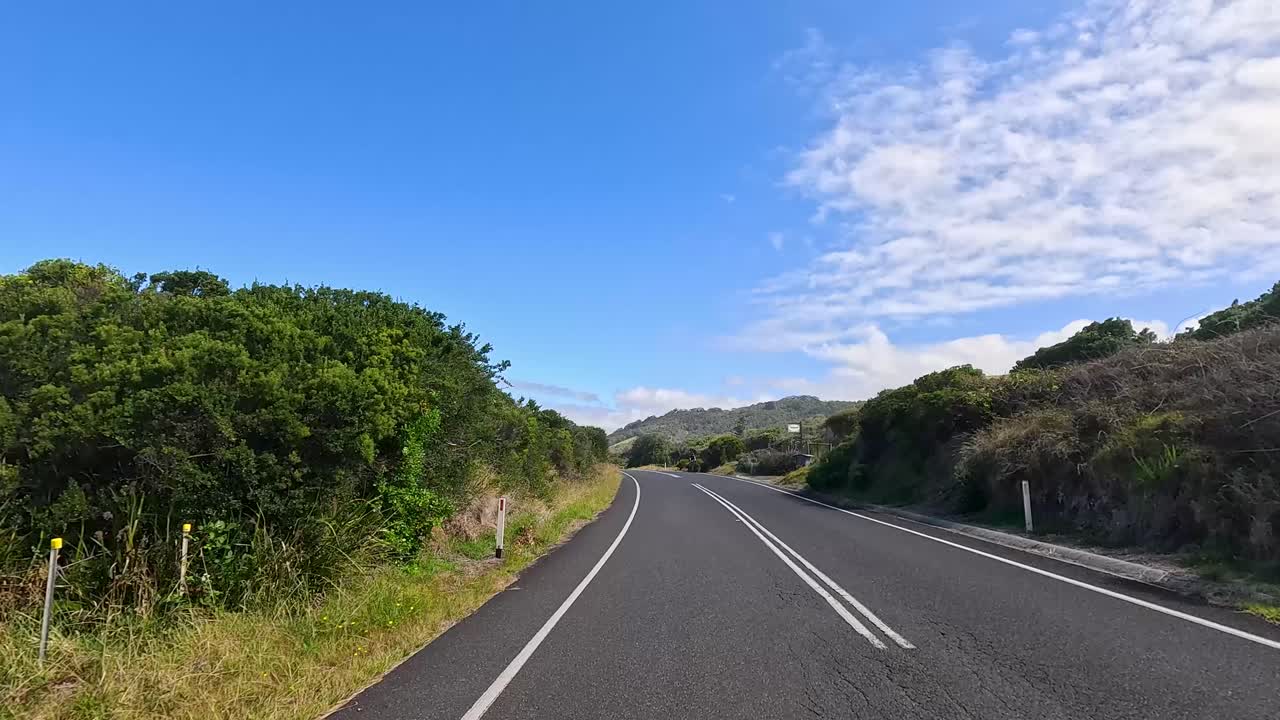 A serene drive along the Great Ocean Road, showcasing lush greenery and coastal views under a bright blue sky