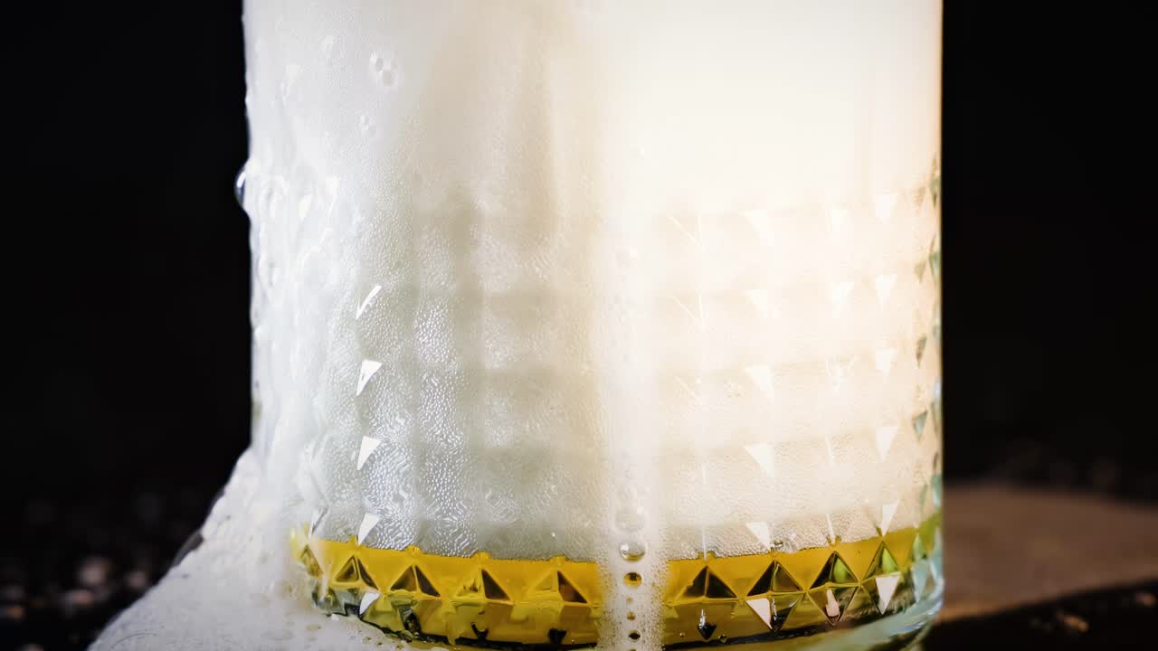 Beer glass overflowing with foam and bubbles