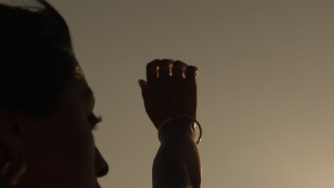 close-up of a woman's face and raised hand in warm sunlight along the coast of portugal, evoking softness and presence