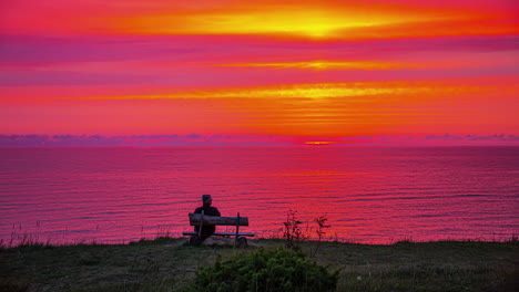 Serenidad-Al-Atardecer:-Timelapse-De-Una-Persona-Observando-Una-Colorida-Puesta-De-Sol-Sobre-El-Océano-Con-Cielos-Morados,-Amarillos,-Azules-Y-Naranjas