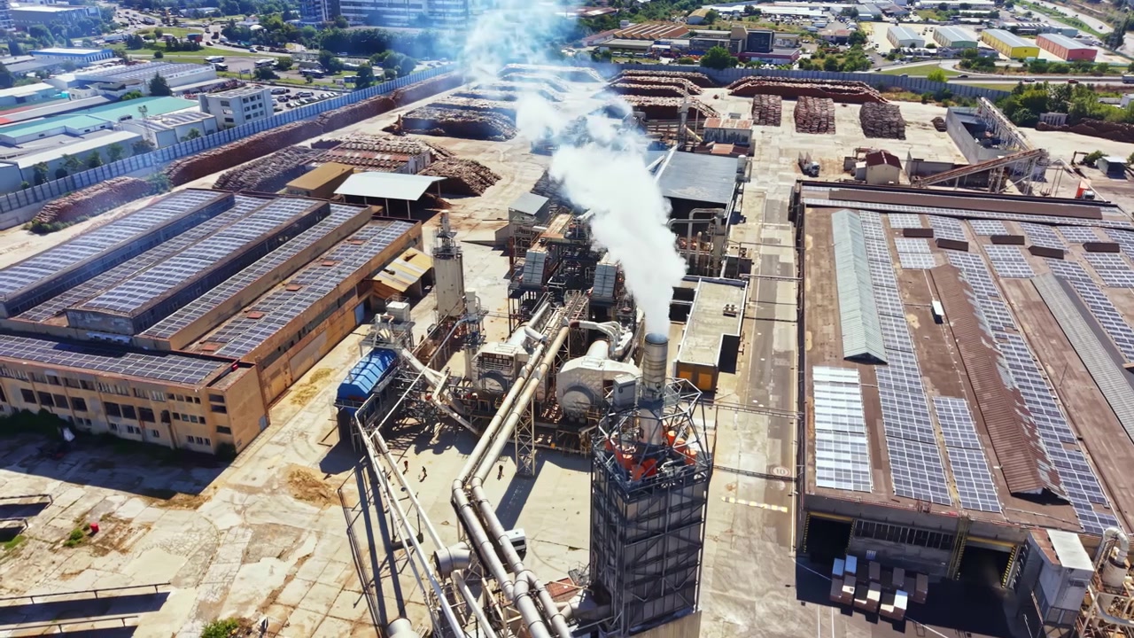 Sito industriale con macchinari e fumo in un ambiente urbano durante il giorno