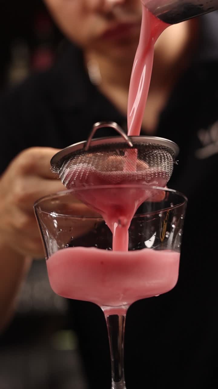 Preparazione di un cocktail rosa con un colino