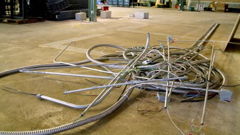 metal electrical conduit on the floor of a warehouse construction site with video dolly right to left.
