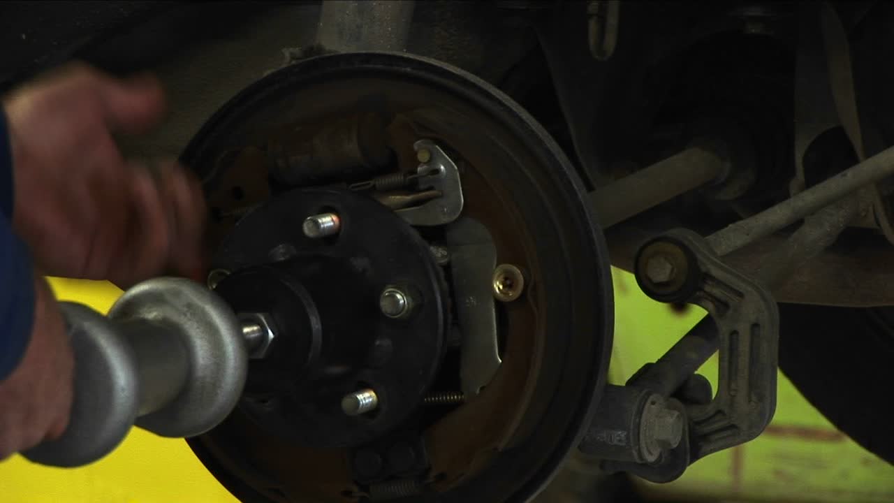 механик затягивает болты на колесе, закрепленном на оси