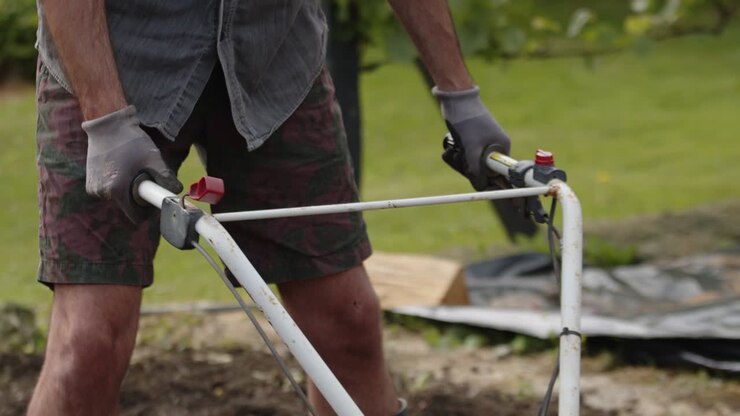 Gardener At Work Holding Rotavator For Garden Cultivation