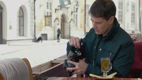 man cleaning camera lens in outdoor cafe