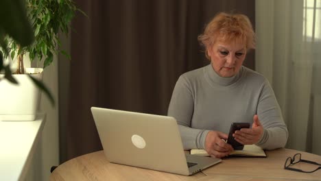 Ältere-Menschen-Arbeiten-Zu-Hause-Am-Laptop.-Porträt-Einer-älteren-Geschäftsfrau,-Die-Zu-Hause-Telefoniert-Und-Aus-Der-Ferne-Am-Computer-Arbeitet