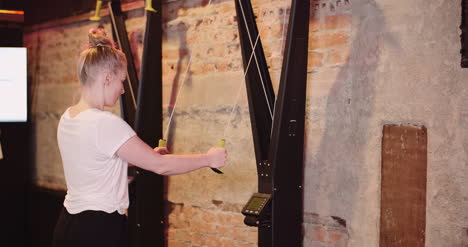 side view of young woman exercising on cable machine at fitness club 3