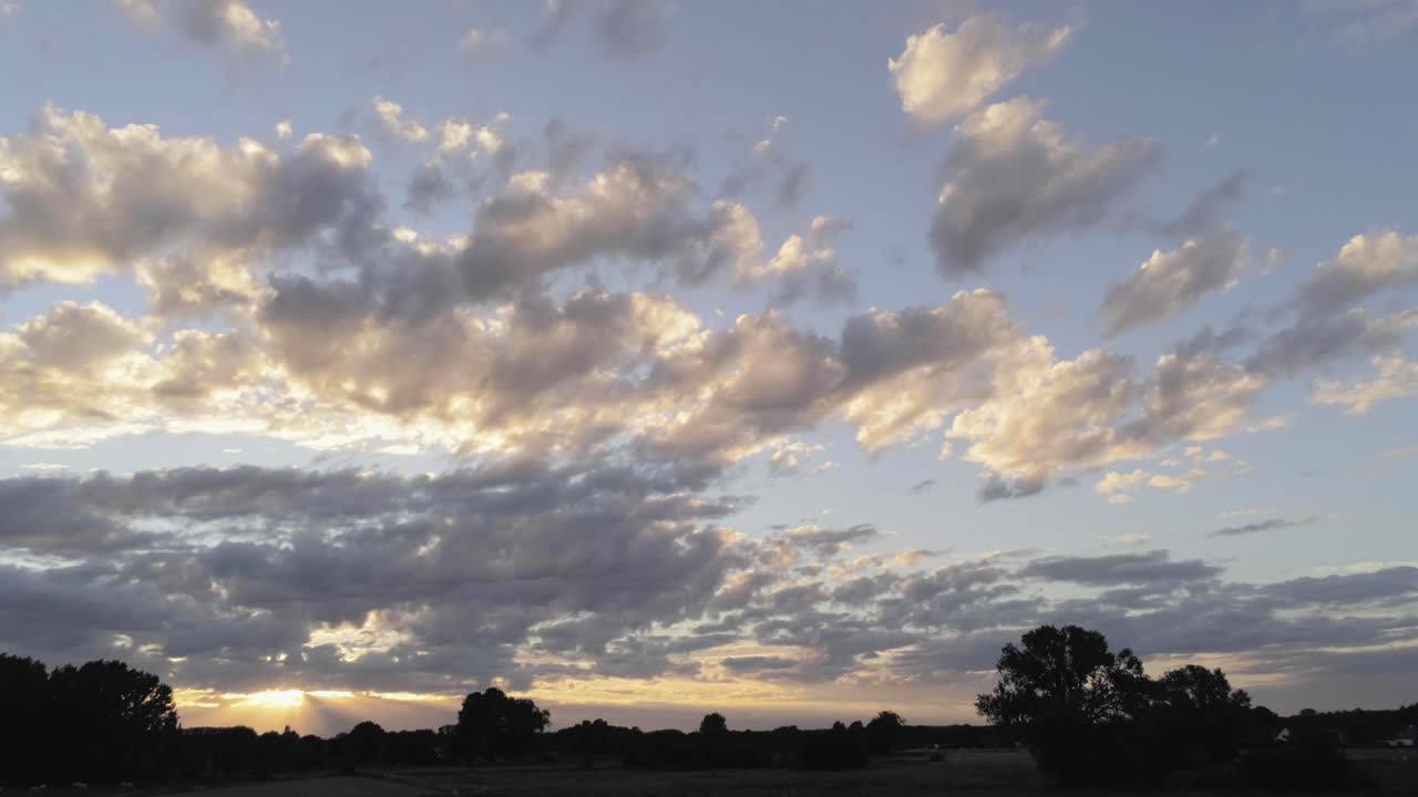 siluetas de campo retroiluminadas, hermosa puesta de sol, nubes de estrato cúmulos en el horizonte, panorámica aérea