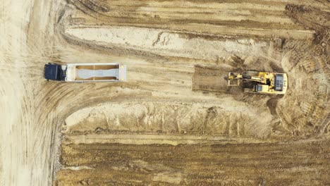 Vista-Aérea-De-Arriba-Hacia-Abajo-De-Una-Excavadora-Que-Carga-Piedra-Triturada-En-Un-Camión-Volquete-En-Una-Cantera-De-Piedra-Triturada