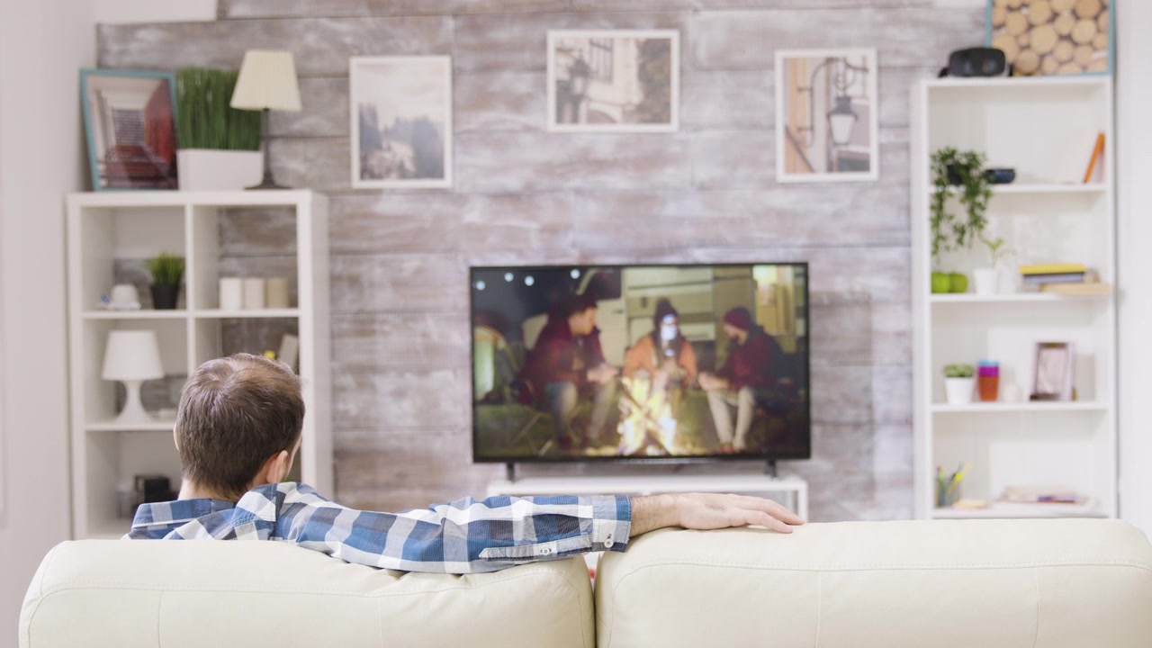 Uomo che si rilassa sul divano guardando la TV a casa