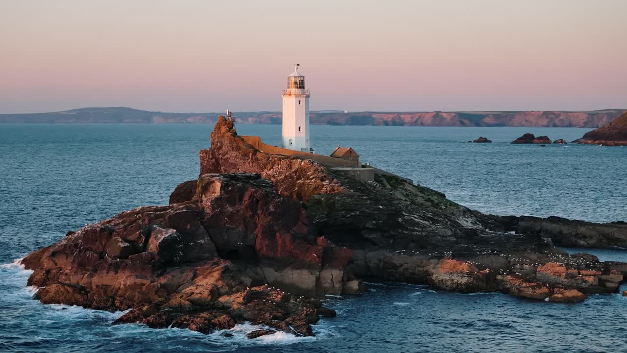 Retreating drone circle left over Godfrey’s Point Lighthouse cliffs with rough sea and empty sky, golden hour backdrop