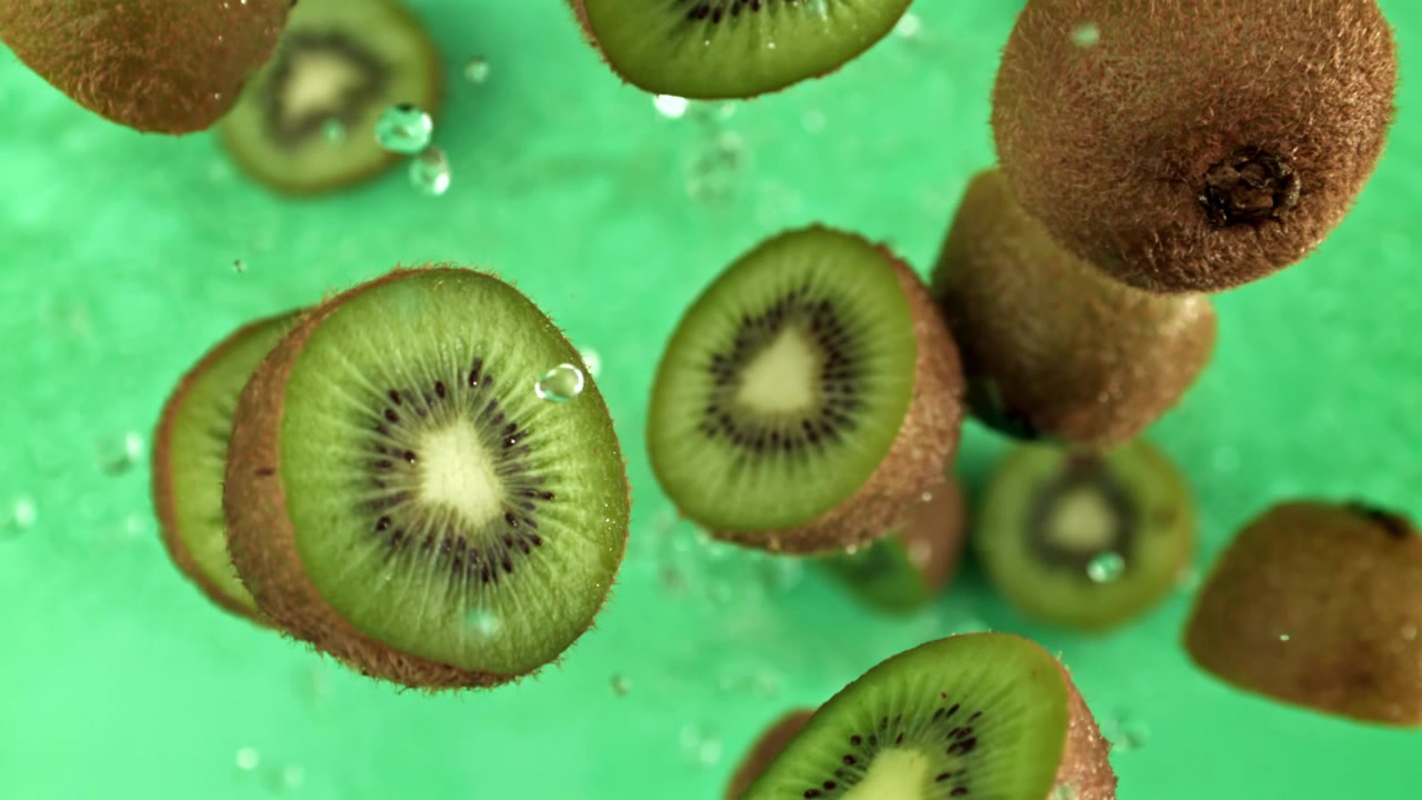 Kiwi fresco cayendo con salpicaduras de agua en súper cámara lenta.
