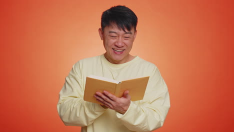 Happy-chinese-man-reading-funny-interesting-fairytale-story-book,-leisure-hobby,-education,-learning