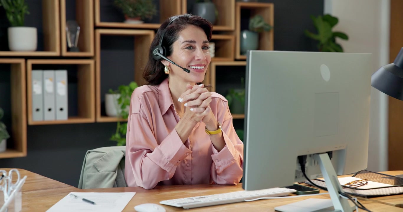 Professionel kvinde arbejder med headset ved kontorbordet