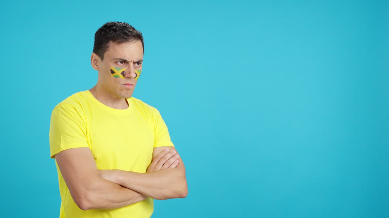 Man with jamaican flag painted looking away with serious expression