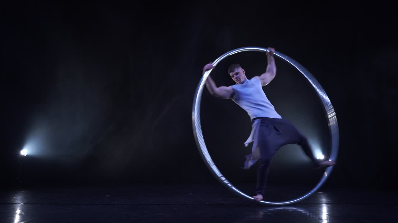 artista de circo muestra concentración y equilibrio mientras gira en una rueda de circo