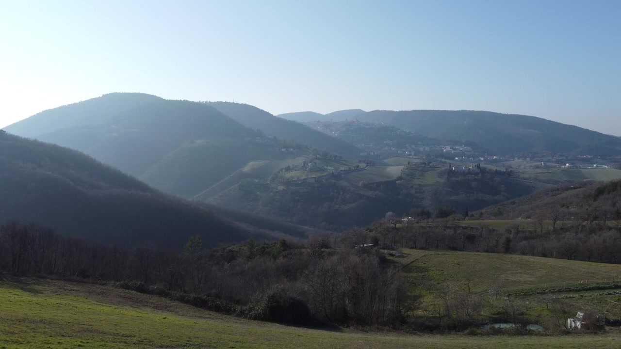 Colinas, bosque, prado, campos al atardecer en Italia, Marcas, Umbría. La ciudad italiana de Arcevia al fondo