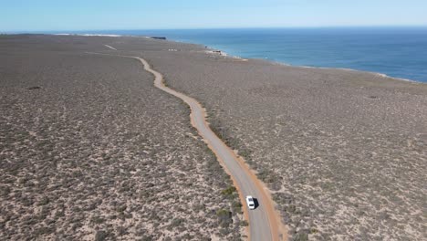 Drohnen-Luftaufnahme-Eines-Lieferwagens,-Der-Auf-Einer-Landstraße-An-Einem-Wunderschönen-Meer-Entlang-Fährt